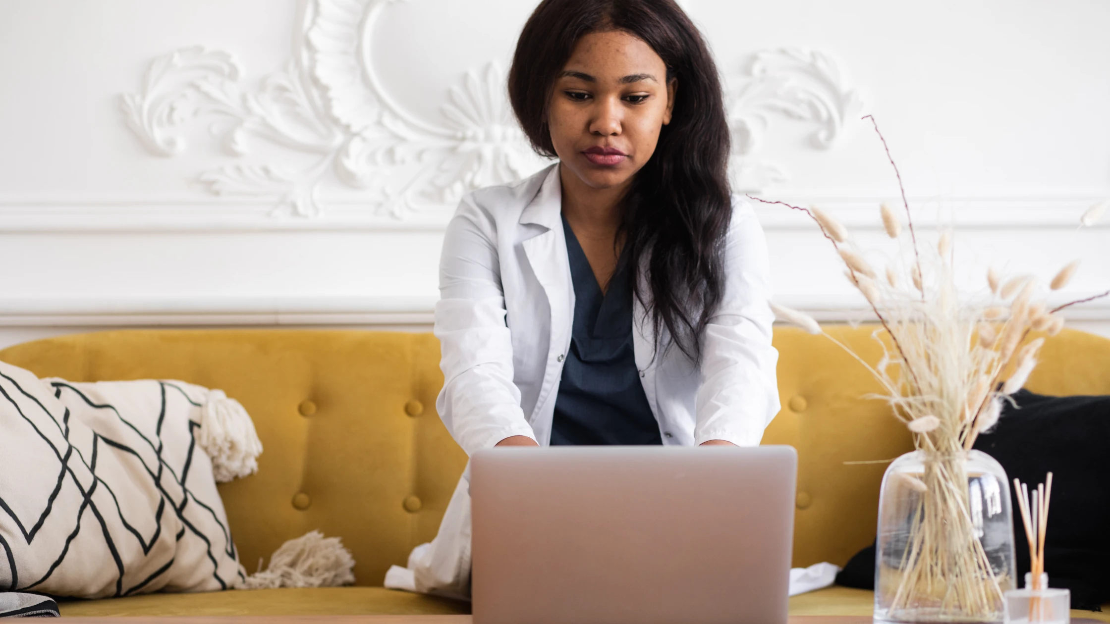 A med school student sitting in front of a laptop in a living room, filling out a transitional residency year application.